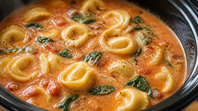Creamy tortellini soup with spinach in a black bowl