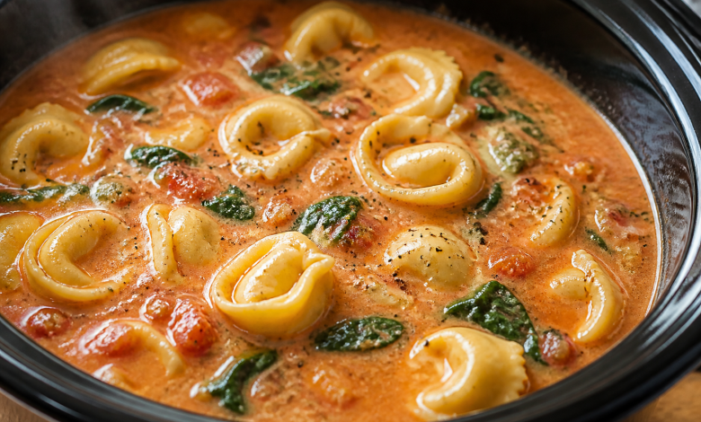 Creamy tortellini soup with spinach in a black bowl