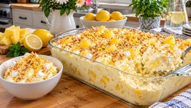 Lemon pineapple cheesecake fluff in a glass dish with graham crumbs and lemon zest