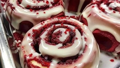 Pan of red velvet cinnamon rolls with cream cheese frosting and red crumbs