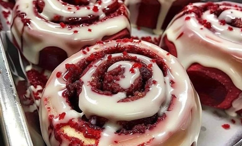 Pan of red velvet cinnamon rolls with cream cheese frosting and red crumbs