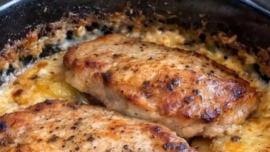 Slow cooker pork chops on creamy potatoes in a black crock