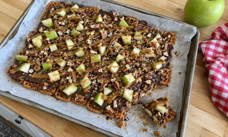 Caramel apple pretzel bark with chocolate, diced green apple, caramel drizzle and sea salt on parchment