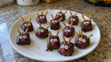 Plate of finished chocolate caramel reindeer with pretzel antlers, candy eyes and red noses