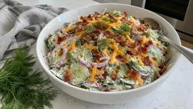 Cucumber ranch salad with crispy bacon, shredded cheddar and fresh dill in a serving bowl