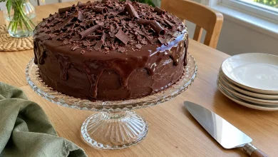 Easy blender chocolate cake with glossy chocolate ganache and chocolate shavings on a glass cake stand
