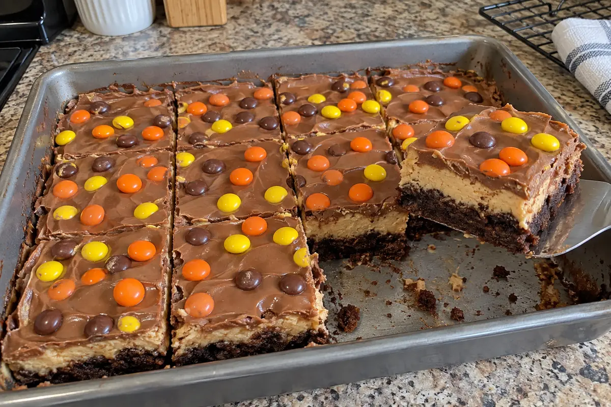 A pan of peanut butter cheesecake brownies cut into squares with a spatula lifting one bar out