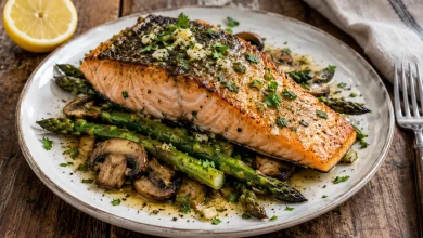 Plated seared garlic butter salmon on asparagus and sliced mushrooms with glossy garlic butter and chopped parsley