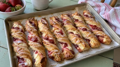 Strawberry cheesecake twists drizzled with glaze on a parchment-lined baking sheet
